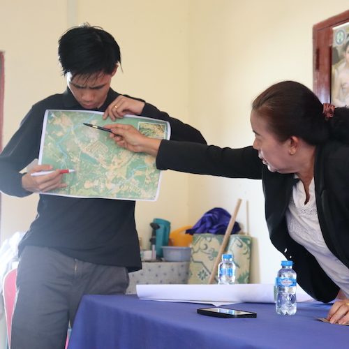 The female chief of Khanmak village helping a male UN-Habitat employee identify areas on a map that are vulnerable to climate hazards