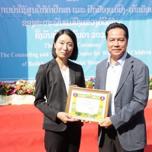 A UN-Habitat Lao PDR representative holding a certificate for the Safer Cities initiative